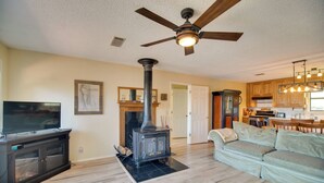 Un salon avec une cheminée, un téléviseur, un canapé et un ventilateur de plafond.