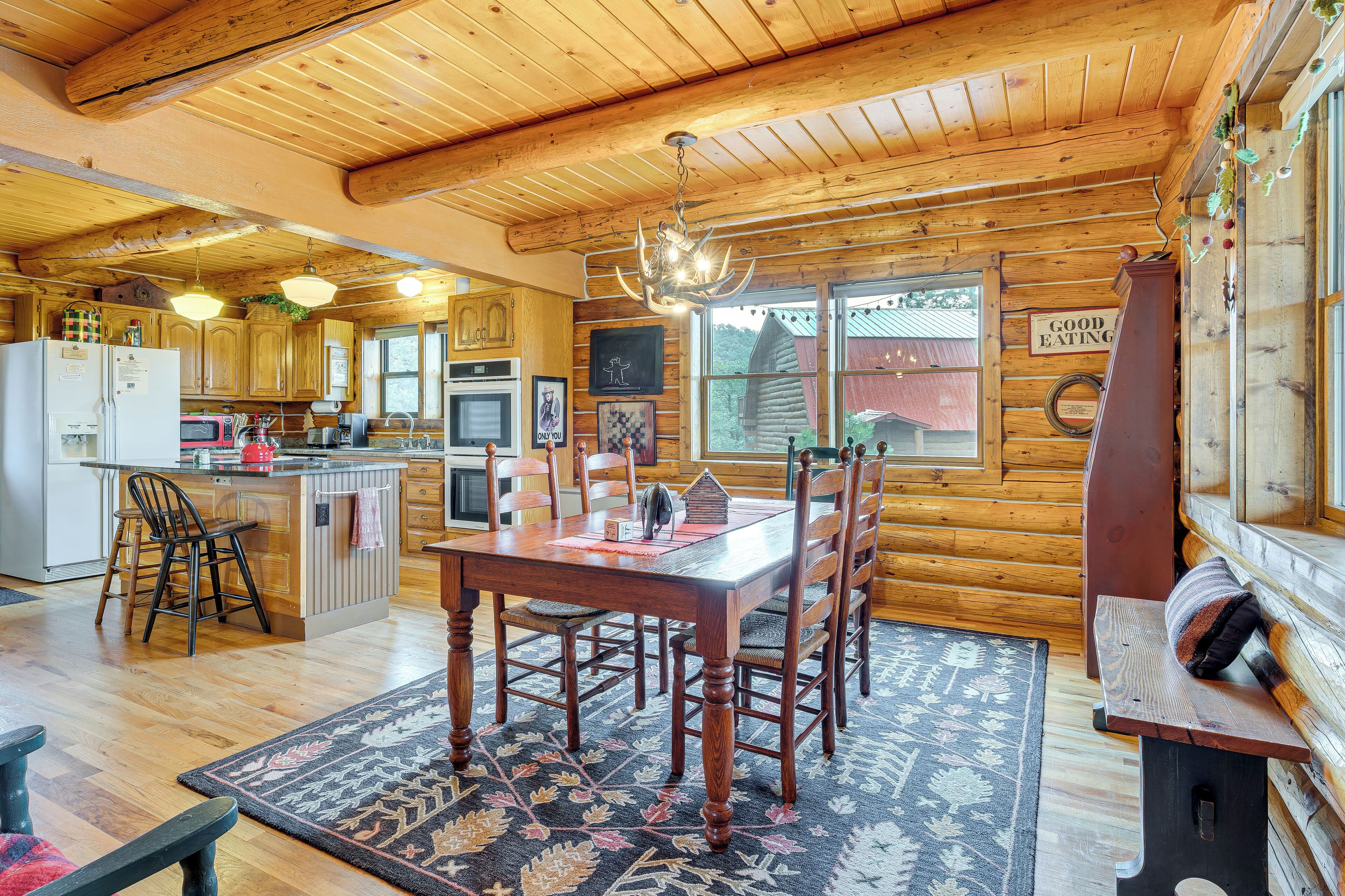A wooden cabin interior with a kitchen, dining area, and a bench with cushions.