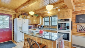 Eine Holzhütte mit einer Küche, einer Kücheninsel, Holzausstattung, einem Kühlschrank, einem Backofen und einer Spüle.