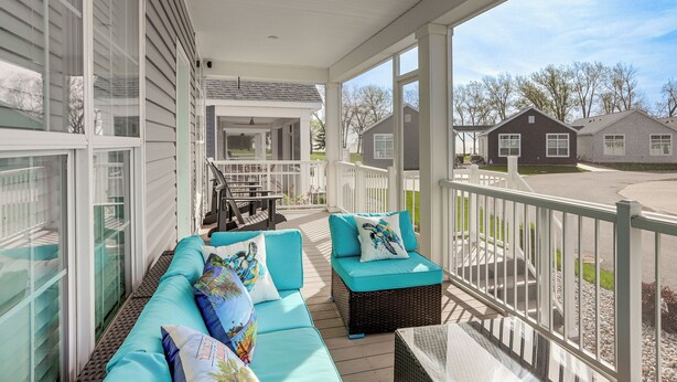 A covered porch with a seating area, a railing, and a view of the neighborhood.