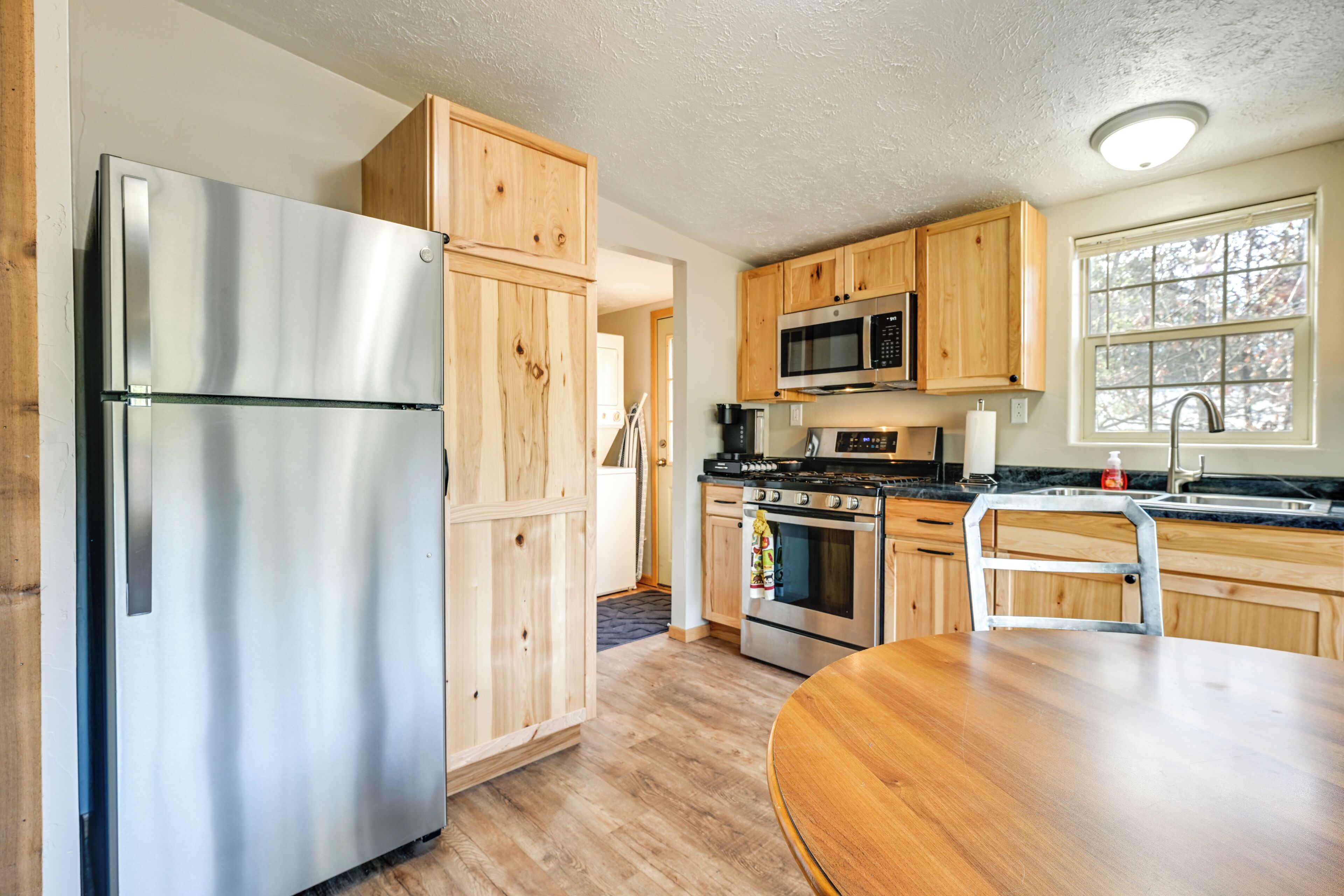 A kitchen with wooden cabinets, stainless steel appliances, and a dining table.