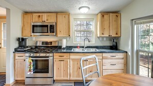 Una cocina con armarios de madera, estufa de acero inoxidable, microondas y un fregadero.