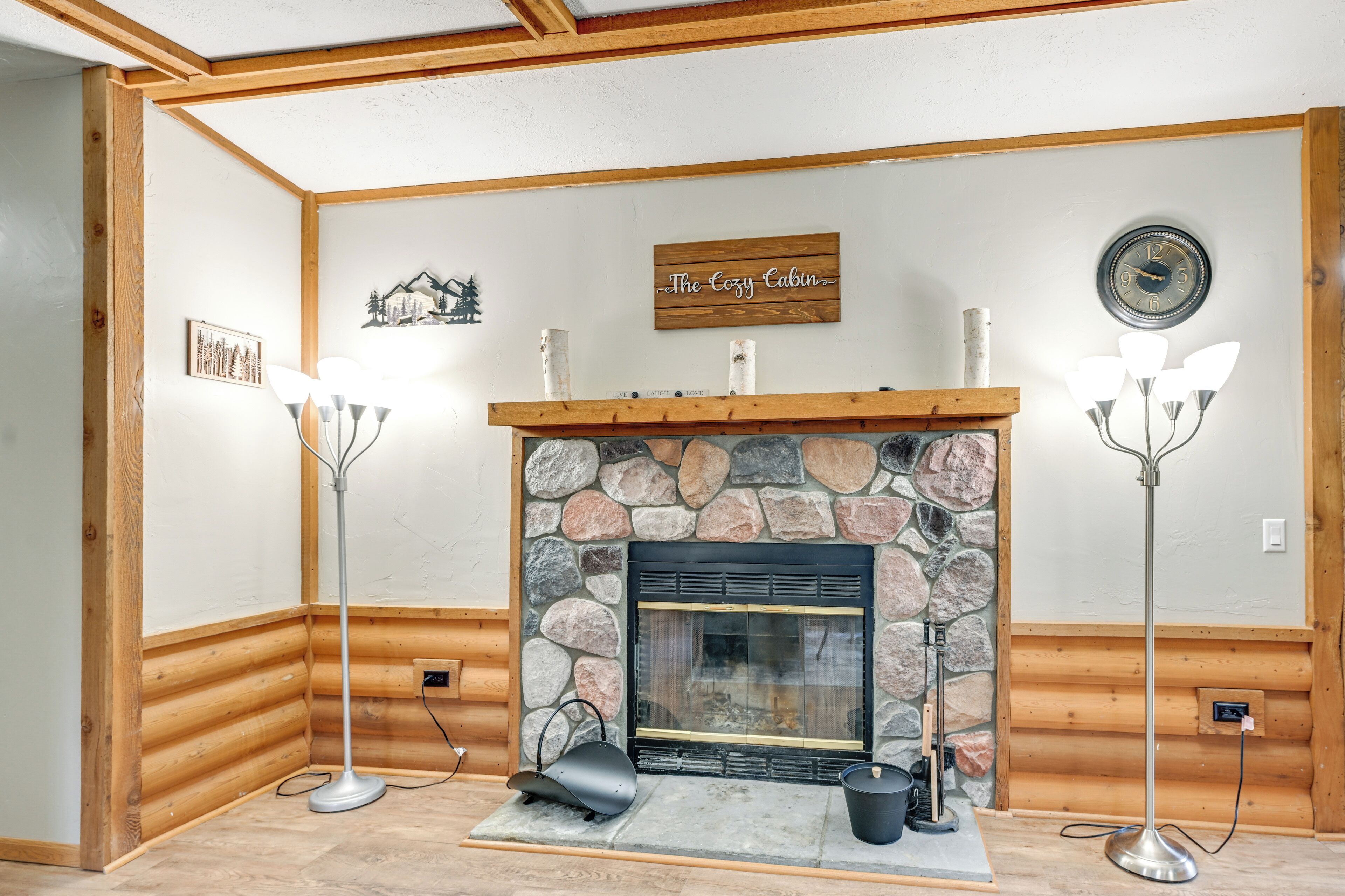 Interior acogedor de una cabaña con chimenea de piedra, paredes de madera y un cartel que dice "The Cozy Cabin".