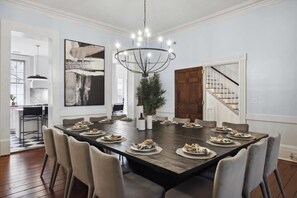 Un comedor con una gran mesa rectangular dispuesta para una comida, rodeada de sillas.