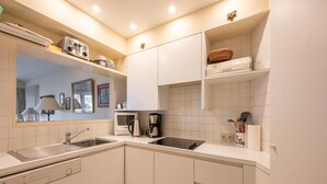 A modern kitchen with a sink, stove, microwave, and coffee maker. - Seaside Villa Apartment (Knokke-Heist)