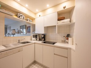 A modern kitchen with a sink, stove, microwave, and coffee maker. - Seaside Villa Apartment (Knokke-Heist)