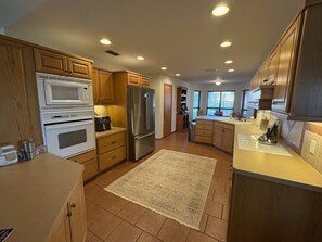 A modern kitchen with wooden cabinets, stainless steel appliances, and a large window providing natural light.