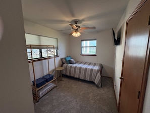 A bedroom with a bed, a ceiling fan, a window, and a wardrobe. - Family Lakefront Home with Large Porch (Graham)