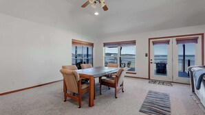A dining area with a table and chairs, a ceiling fan, and large windows with views.