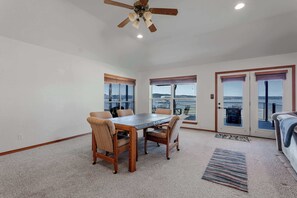 A dining area with a table and chairs, a ceiling fan, and large windows with views.