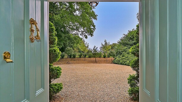 A gravel pathway leading to a door with a decorative handle. - Ttich Manor Retreat (Milton Keynes)