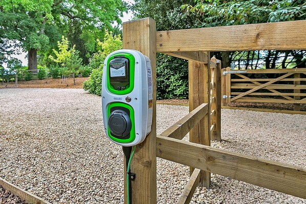 Un chargeur électrique portatif pour clôture, fixé sur un poteau en bois.