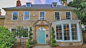 A stone building with a green door, multiple windows, and a bay window. - Ttich Manor Retreat (Milton Keynes)