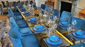 A formal dining room with a long table set for six, blue upholstered chairs, and a fireplace in the background. - Ttich Manor Retreat (Milton Keynes)
