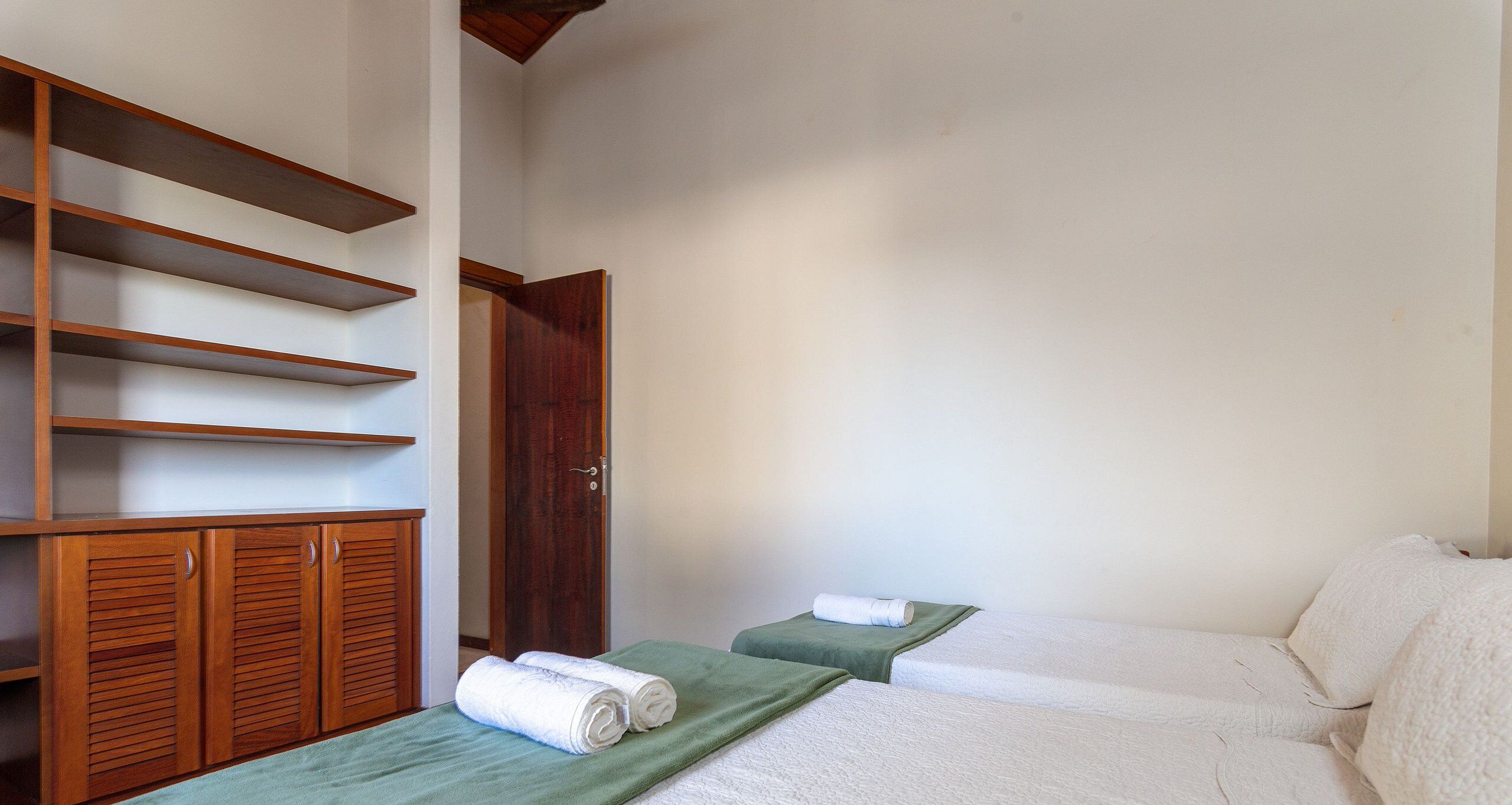 Una stanza con due letti, mobili in legno e una porta.