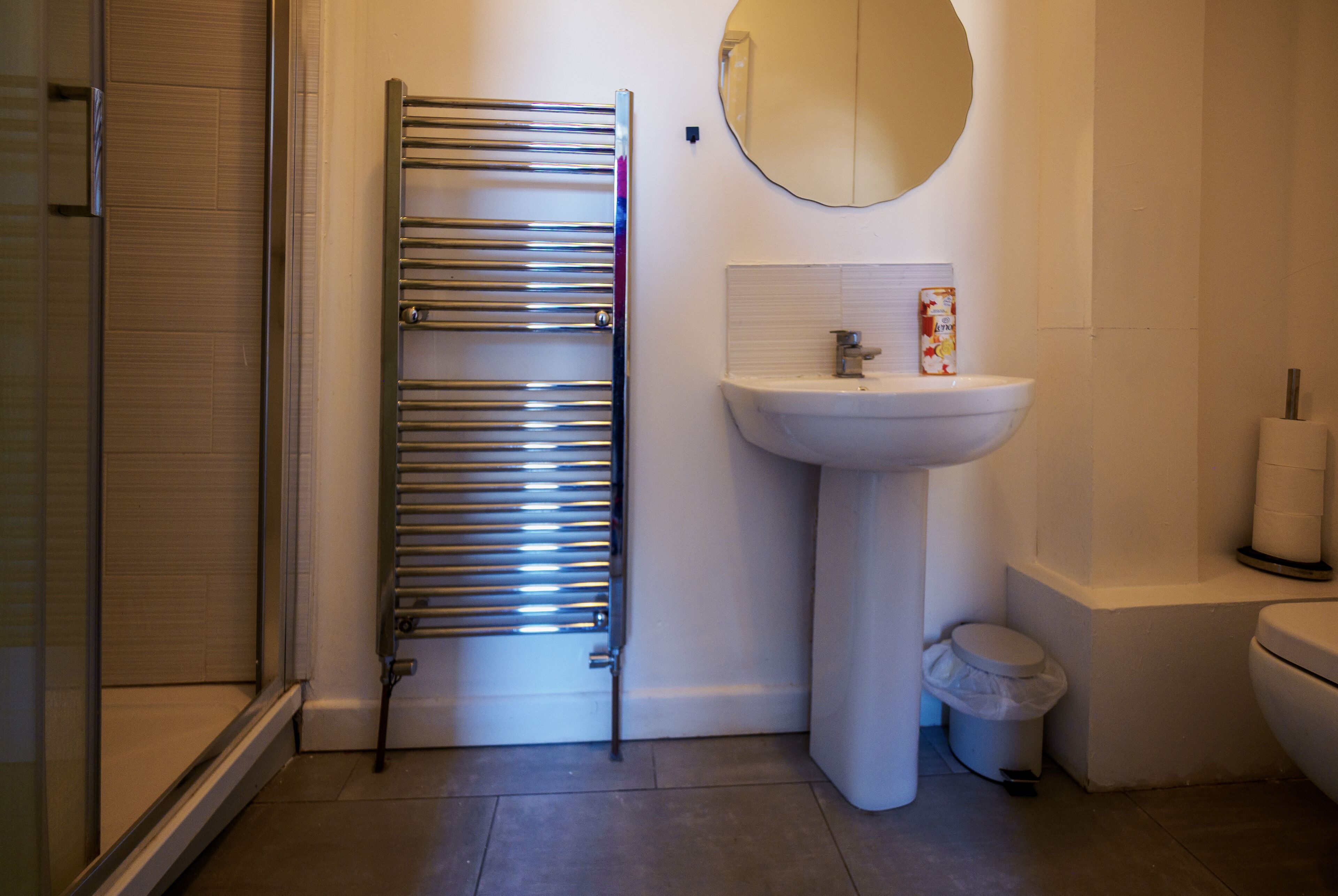 Un bagno con portasciuga asciugamani, lavandino, water e cestino.