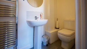A bathroom with a white sink, toilet, and a mirror above the sink. - WoodHus Lodge  Cosy Large Family  Room 4 (Stoke-on-Trent)