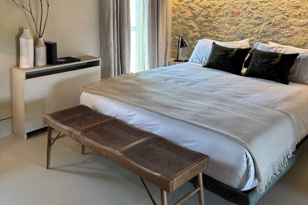 A bedroom with a bed, bedside table, lamp, and a decorative wall.