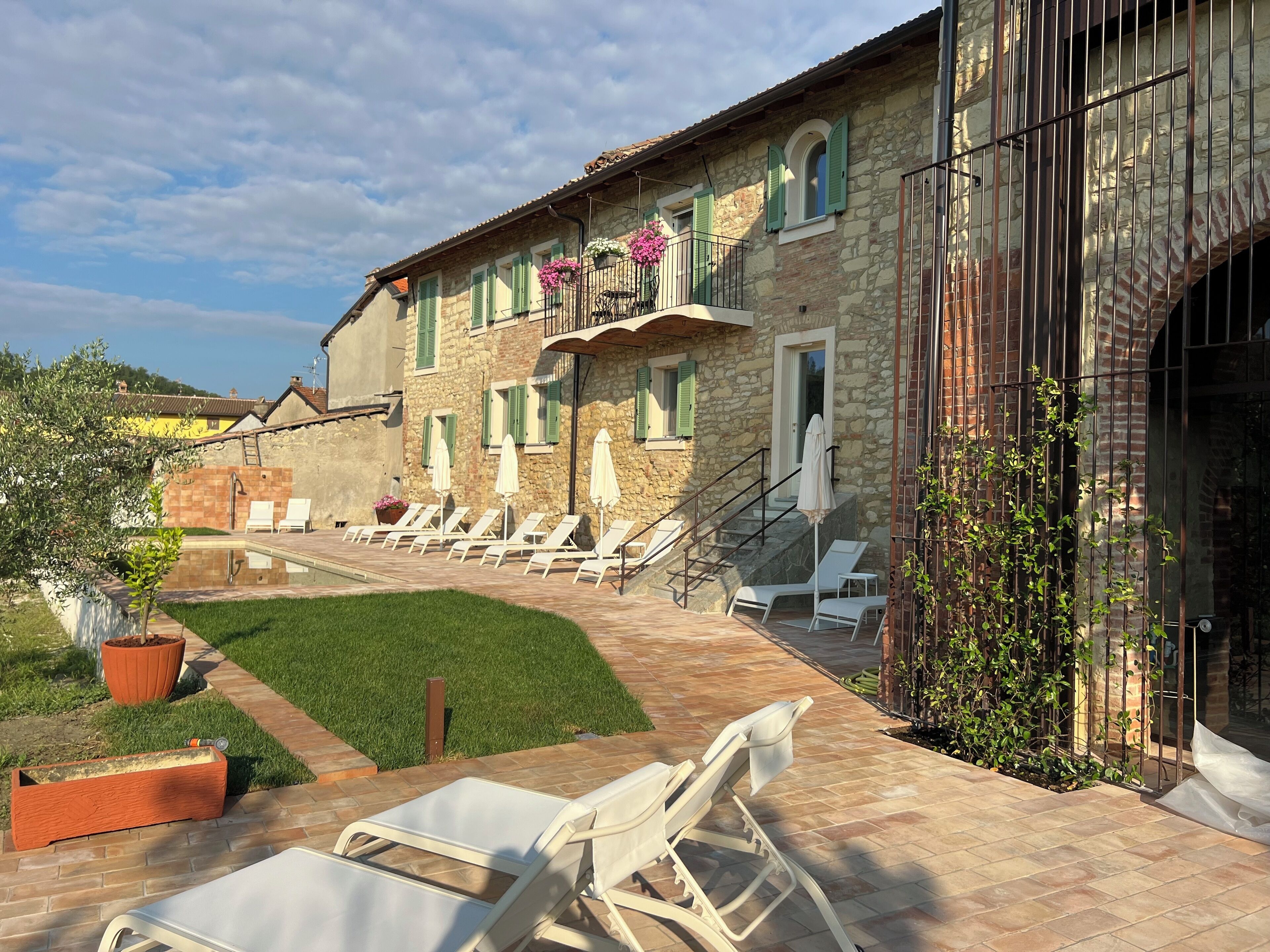 A stone building with a balcony, outdoor seating, and a swimming pool.