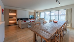 Un salon moderne avec une table à manger en bois, des canapés et un téléviseur.