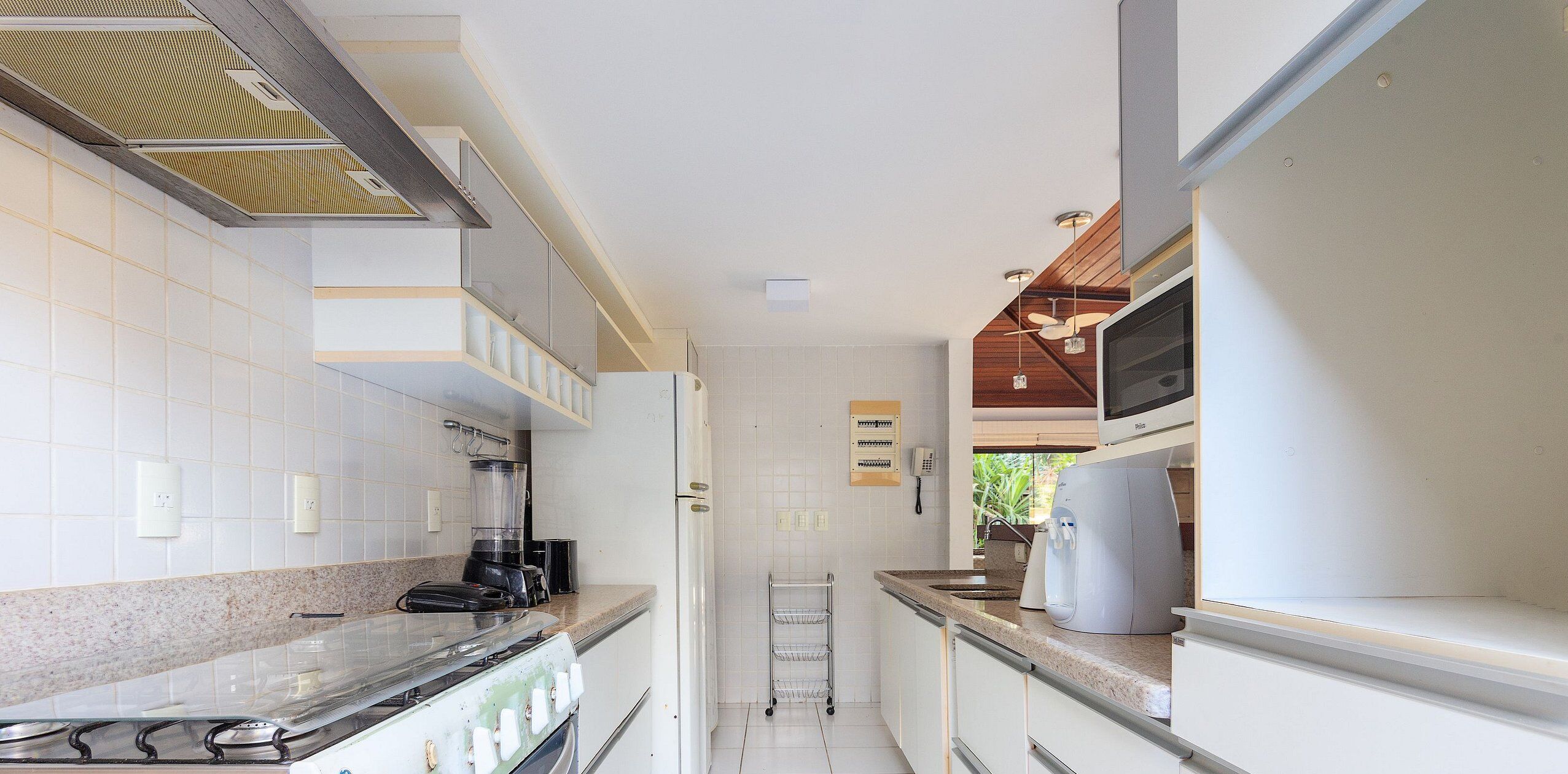 Een moderne keuken met witte kastjes, een granieten aanrechtblad, een inbouwoven, een magnetron en een koffiezetapparaat.