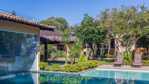 A pool area with a clear view of the pool, lounge chairs, and surrounding greenery. - Bz55 Casa 200m da praia com 4 suítes (Buzios)