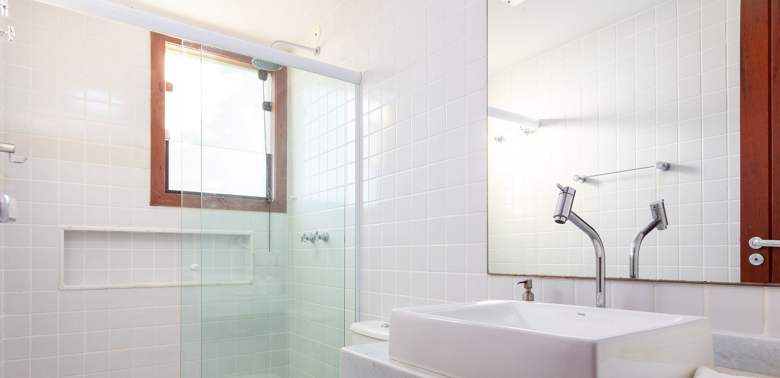 A modern bathroom with a glass-enclosed shower, a white sink, and a large mirror.