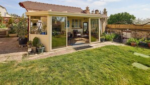 A conservatory with a glass door, a patio with outdoor furniture, and potted plants. - Gîte between the Seine and the cliffs near GIVERNY and the Château de la Roche Guyon (Gommecourt)