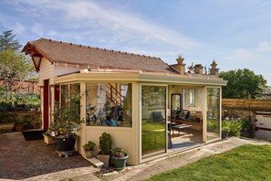 A glass-enclosed patio with a view of a garden and a patio chair. - Gîte between the Seine and the cliffs near GIVERNY and the Château de la Roche Guyon (Gommecourt)