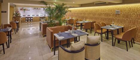 A restaurant with a bar area, multiple tables and chairs, and a decorative wall.