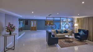 A spacious lobby with a modern design, featuring a sofa set, a coffee table, and a decorative vase. - Grand Continent T Nagar (Chennai)