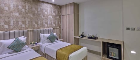 A hotel room with two beds, a ceiling fan, a minibar, and a small fireplace.