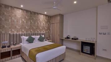 A modern hotel room with a large bed, a ceiling fan, a built-in TV, and a fireplace.