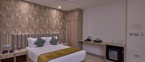 Una habitación de hotel moderna con una cama grande, un ventilador de techo, televisor integrado y una chimenea.