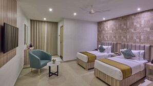 A hotel room with two beds, a TV, a ceiling fan, and a small table with a plant. - Grand Continent T Nagar (Chennai)