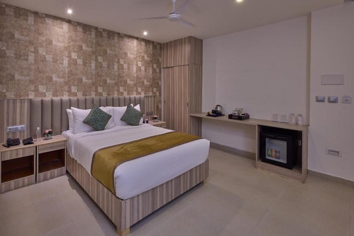 Une chambre d’hôtel moderne dotée d’un grand lit, d’un ventilateur de plafond, d’un téléviseur intégré et d’une cheminée.