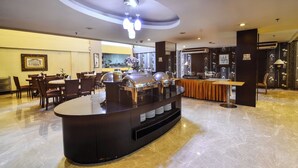 A modern hotel lobby with a buffet station, seating area, and a bar. - Losari Roxy Hotel Jakarta (Jakarta)