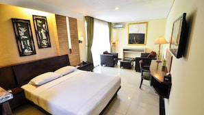 A hotel room with a large bed, a desk, a chair, a sofa, and a TV. - Losari Roxy Hotel Jakarta (Jakarta)