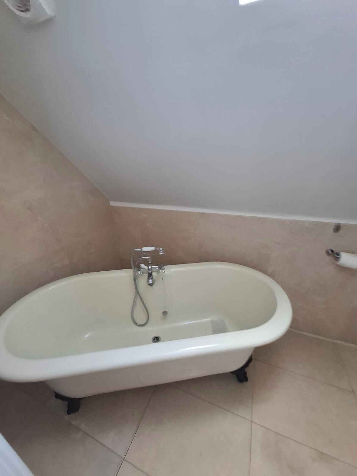 A bathroom with a freestanding bathtub, a toilet, and a towel rack.