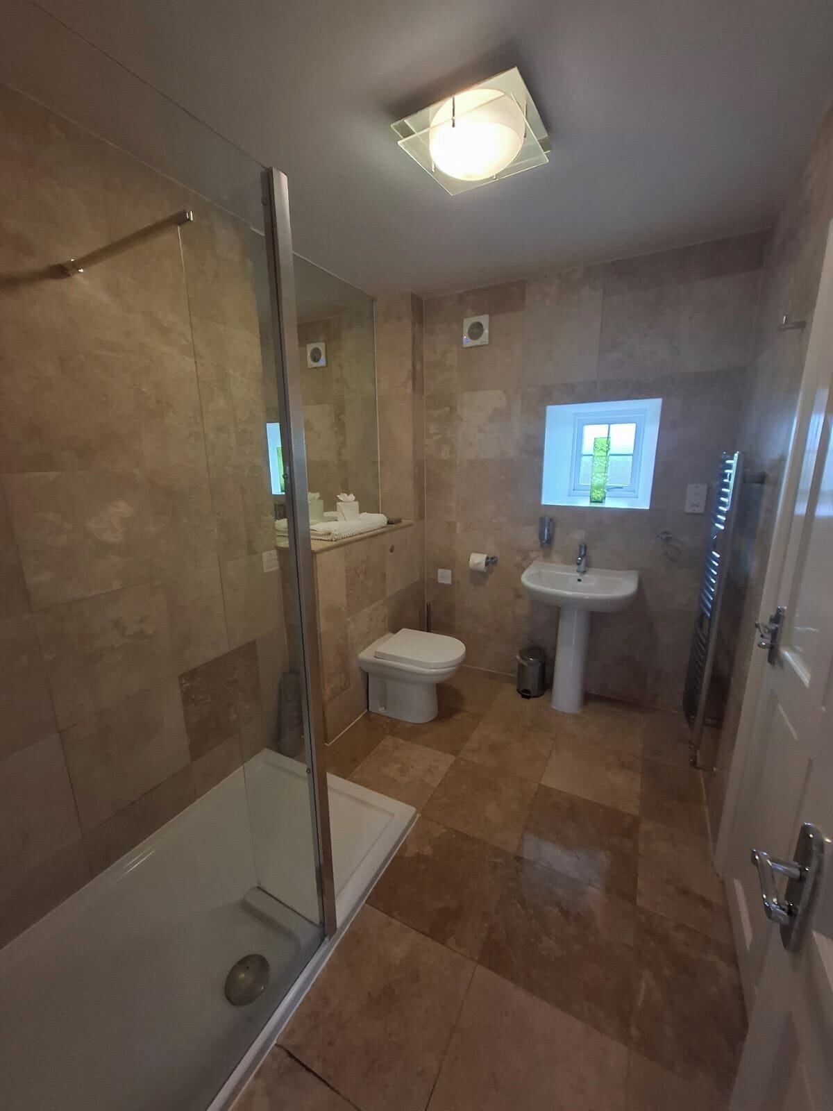 Une salle de bain avec une douche à parois de verre, des toilettes et un lavabo.