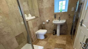 A bathroom with a glass shower enclosure, a white toilet, a pedestal sink, and a mirror above the sink. - Modern Apartment - Quiet Location (Doncaster)