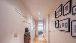 A hallway with framed photographs on the walls, a wooden sculpture, and a door with a light switch. - Apartment in Knokke-heist Near Lippenslaan (Knokke-Heist)