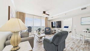Amplia sala de estar con televisor grande, asientos cómodos y un balcón con vistas.