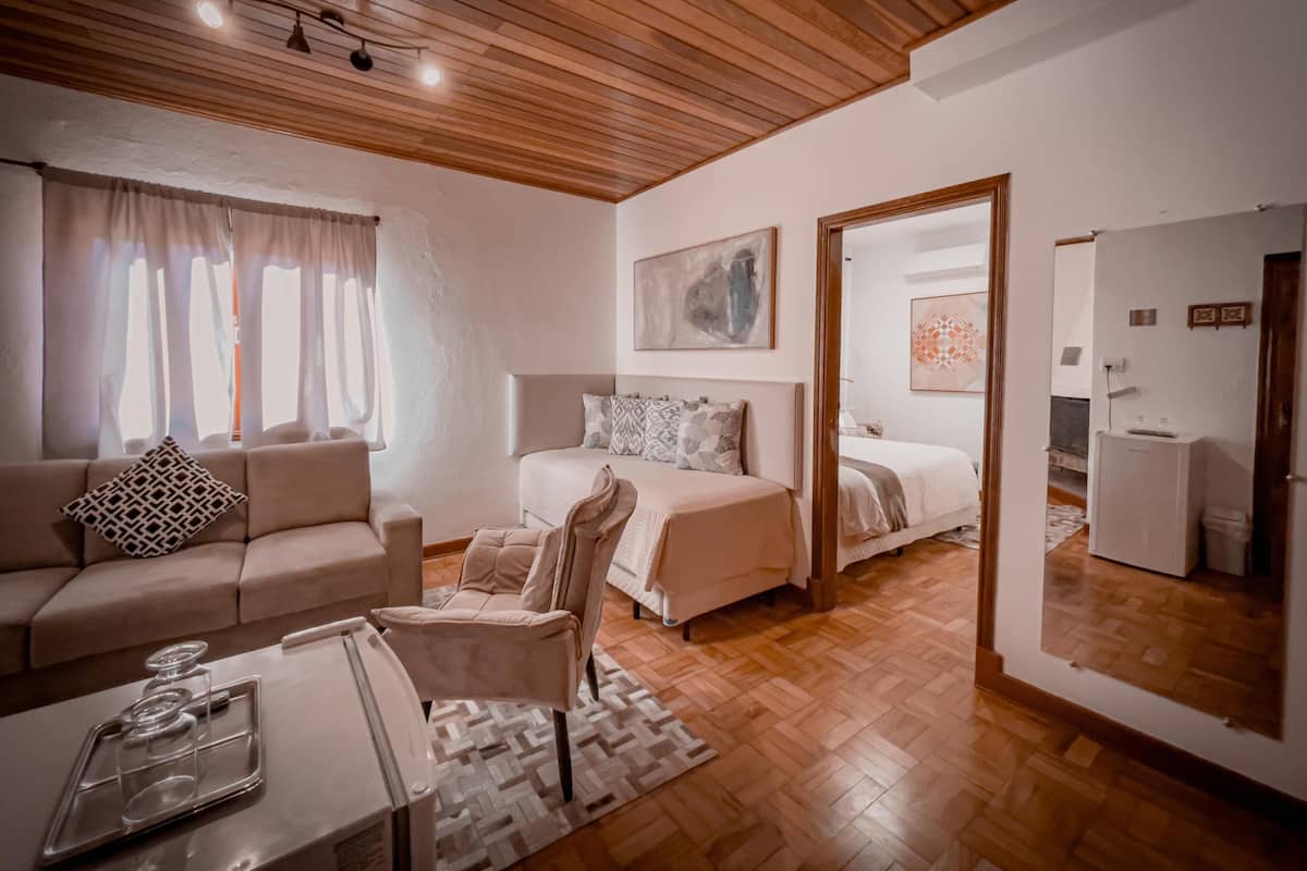 A modern bedroom with a wooden ceiling, a sofa, a chair, a bed, and a mirror.