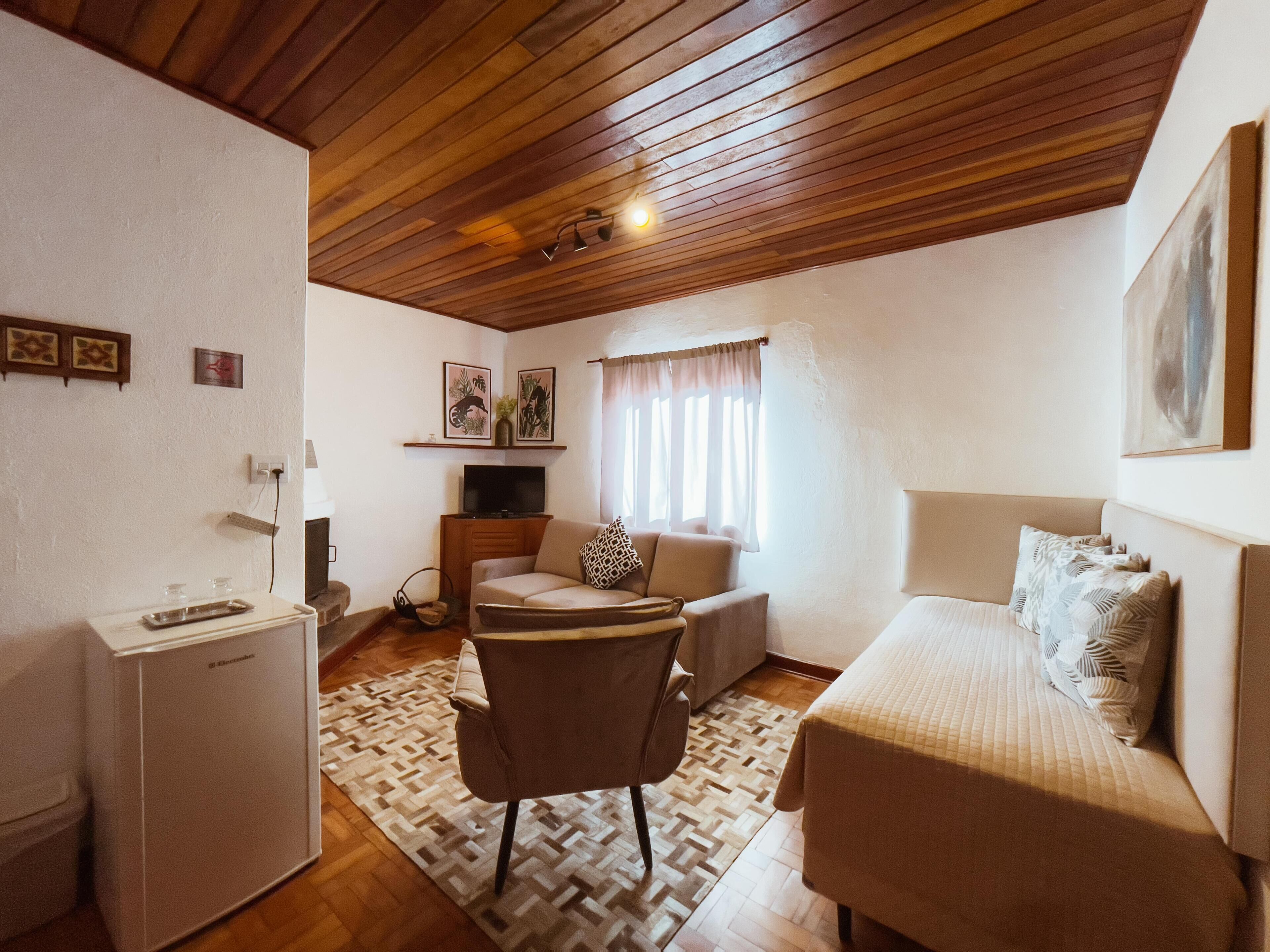 Una habitación compacta con cama, sofá, una mesita y televisor.