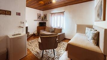 Una habitación compacta con cama, sofá, una mesita y televisor.