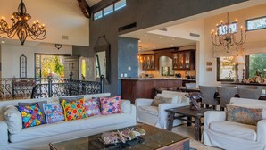 A spacious living room with a white sofa, colorful cushions, a glass coffee table, and a chandelier. - Luxury Cabo Del Sol Oceanfront Villa w/ Infinity Pool, Walk to Beach & Golf View (Corridor)