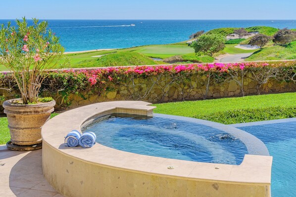 A swimming pool with a view of the ocean and a golf course.