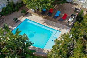 Une piscine dotée d’une terrasse carrelée, entourée de plantes en pot et de mobilier d’extérieur.