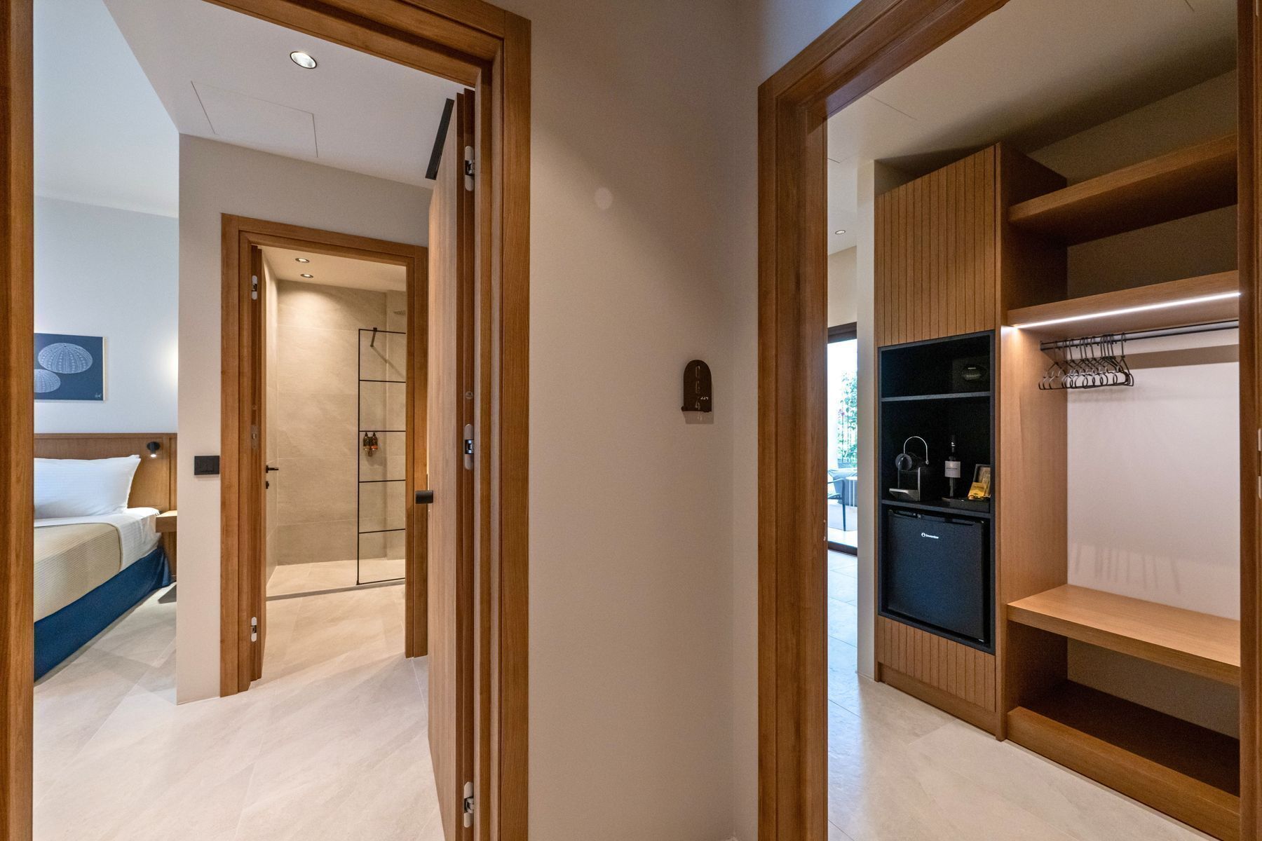 A hotel room with a bed, a bathroom, and a wardrobe with shelves.